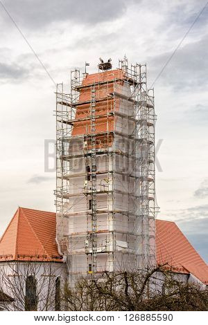 two storks in their nest above a scaffolded church spire