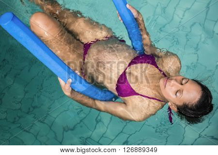 Pregnant woman with foam roller in the pool