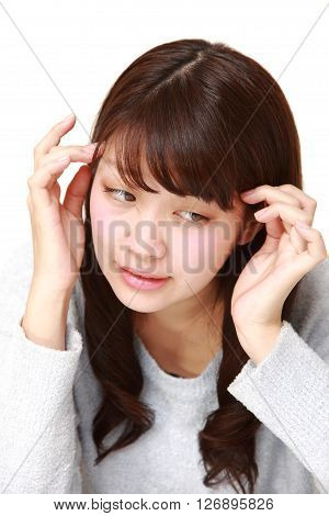 young Japanese woman suffers from headache  on white background