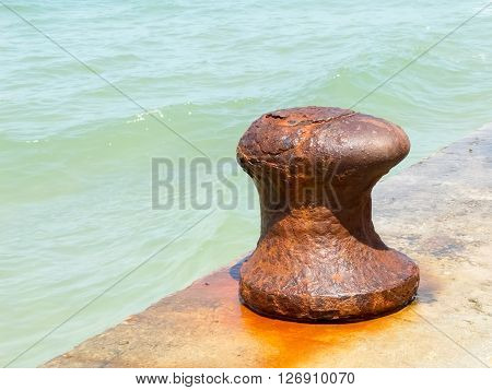 Old iron rusty mooring bollard at a harbor