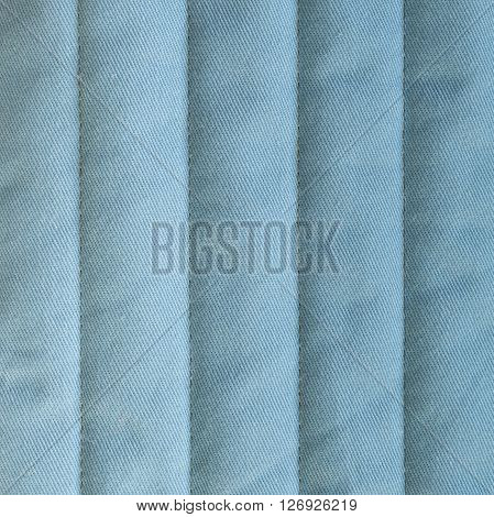 Pale blue textiles with insulation. Vertical stripes. Close up fragment of the top view.