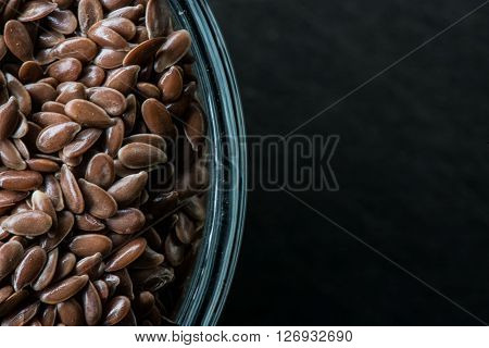 Edge of Bowl of Brown Flax Seed with Copy Space on black slate cutting board