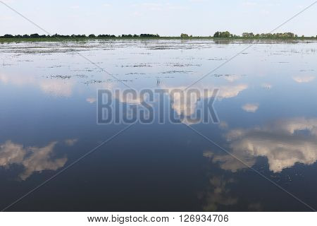 Blue summer sky and reflection of clouds in the surface of the Volga river. Nature landscape view in Russian countryside.