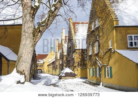 Augsburg Germany - January 17 2016: The Fuggerei and tourists.The Fuggerei is the world's oldest social housing complex still in use. It is a walled enclave within the city of Augsburg Bavaria.