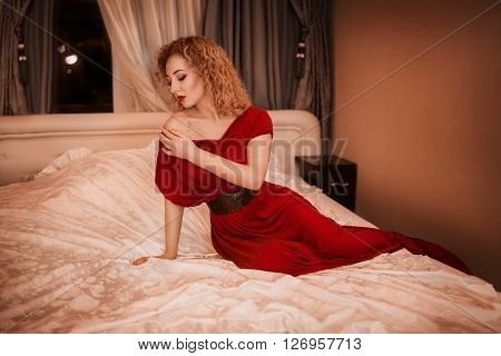 Sexy beautiful girl in evening dress on the bed