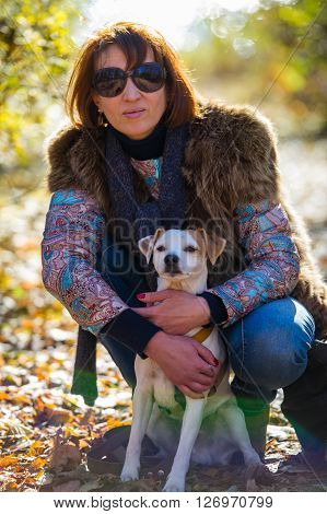 portrait of a woman with a dog on holiday in the autumn park  age of 40 years