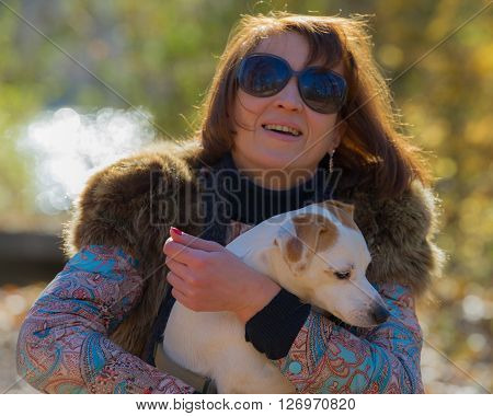 portrait of a woman with a dog on holiday in the autumn park  age of 40 years
