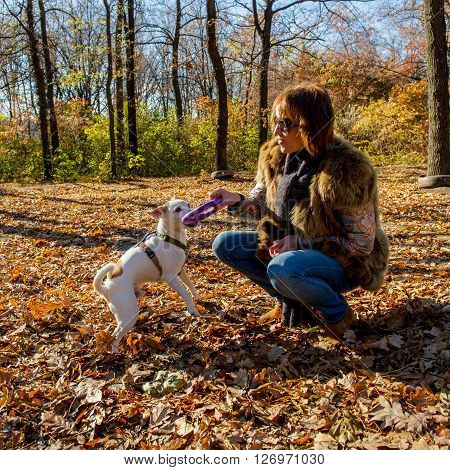 Woman playing with dog in autumn park the age of 40 years