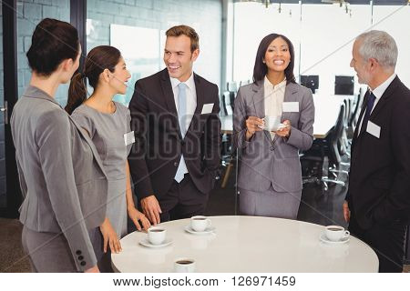 Businesspeople having tea and interacting during breaktime in office