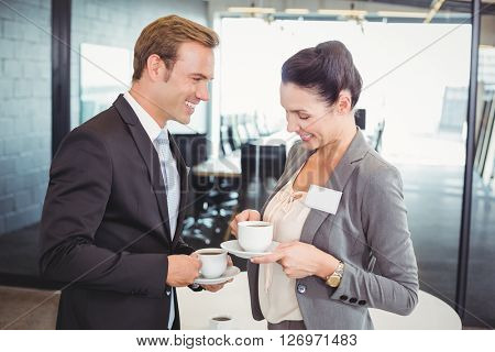 Businessman and businesswoman having tea during breaktime in office