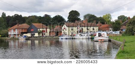 The Riverside In The Village Of Coltishall, Norfolk Broads, Uk With Boats And Local Pub