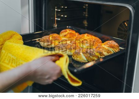Woman Cooking In The Kitchen, Puts Cakes In The Oven In The Kitchen