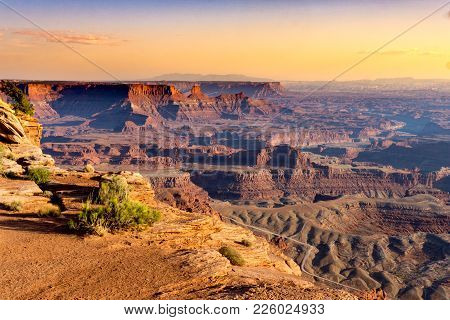 High, Hazy View Of The Rugged Desert Terain, Mountains And Canyons At Sunset