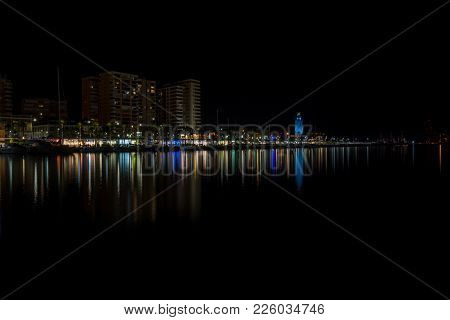 View Of Malaga City And Lighthouse And Their Reflections On Water From Harbour, Malaga, Spain, Europ