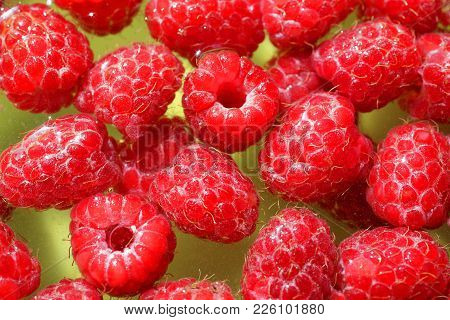 Delicious First Class Fresh Raspberries Floating In Water On Yellow Background