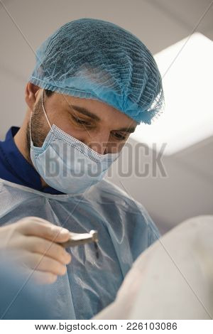 Doctor With Drill In Hand Looking At A Patient In Stomatology Room, Close Up