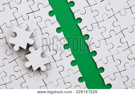 The Green Path Is Laid On The Platform Of A White Folded Jigsaw Puzzle. The Missing Elements Of The 