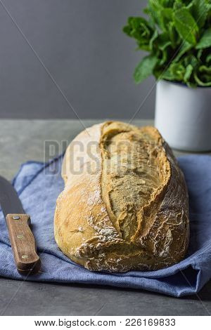 Freshly Baked Hand Crafted Rustic Bread Loaf On Blue  Linen Towel On Dark Kitchen Table Knife Green 