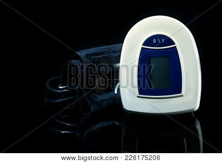 Blue-white Digital Blood Pressure Monitor With Wide Range Cuff Isolated On Dark Background. Health C