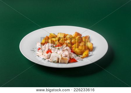 Chicken, Turkey With Cream Sauce And Red Pepper, Fried Potatoes. On A White Plate. Green Background.