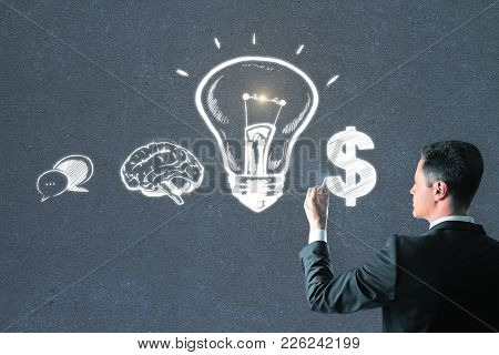 Handsome European Businessman Drawing Creative Business Sketh On Concrete Wall Background. Leadershi