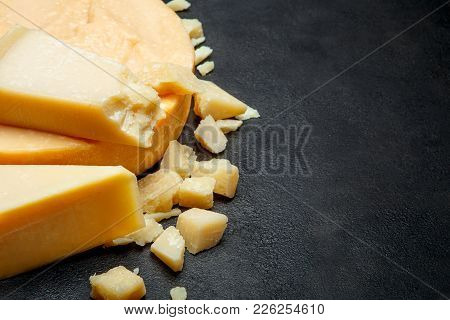 Head Of Parmesan Or Parmigiano Hard Cheese And Pieces On Concrete Background Or Table