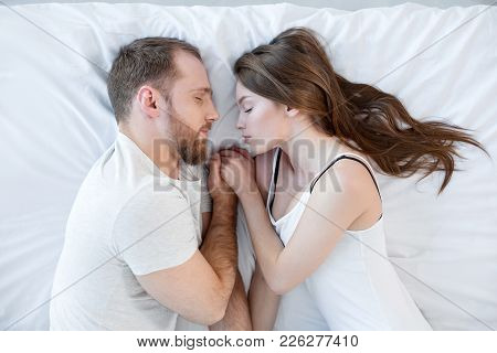 Good Night. Attractive Young Loving Man And Woman Sleeping Together And Holding Hands And Wearing Cl