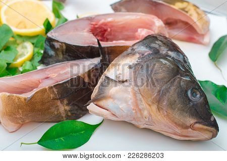 Raw Fish With Greens On A White Cutting Board.