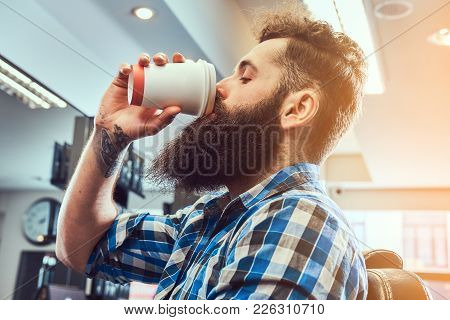 Close-up Portrait Of A Handsome Stylish Bearded Male With A Tattoo On Arm Dressed In A Flannel Shirt