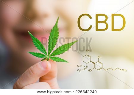 Smiling Kid Child Holding A Hemp Leaf. Concepts Of Using Marihuna For Medicinal Purposes For Childre