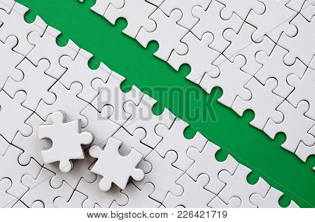The Green Path Is Laid On The Platform Of A White Folded Jigsaw Puzzle. The Missing Elements Of The 