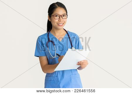 Cheerful Medical Intern Making Notes On Paper And Looking At Camera. Happy Young Asian Surgeon In Un