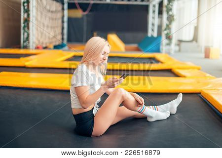 Caucasian Women Use Her Smart Phone For Texting For Her Boyfriend In The Trampoline