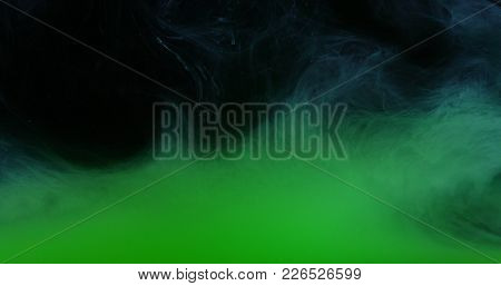 Green Drops, Waves And Clouds Of Ink Creating Dynamic Shapes In Water. Abstract Effects Of Paint Col