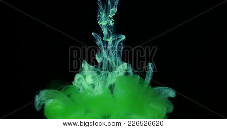 Green Drops, Waves And Clouds Of Ink Creating Dynamic Shapes In Water. Abstract Effects Of Paint Col