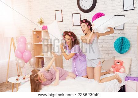 Three Girls With Curlers In Their Hair Pillowfight. They Are Celebrating Women's Day March 8.