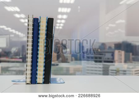 Notebook With Bookend On Shelf In Office