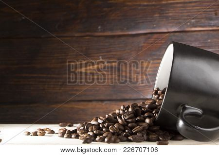 Seeds Of Coffee In A Black Cup On A Wooden Background Close Up