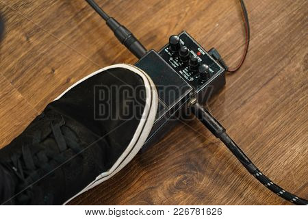 Man With Musical Instrument Setting Up Guitar Audio Stomp Box Effects And Cables In Music Studio