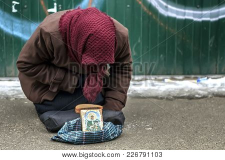 An Elderly, Homeless Woman Asks For Mercy From Indifferent Passers-by. The Concept Of Poverty, Indif
