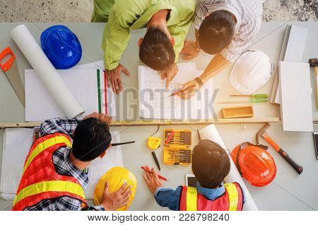 Top View Of Group Of Engineer, Technician And Architect Planning About Building Plan With Blueprint 