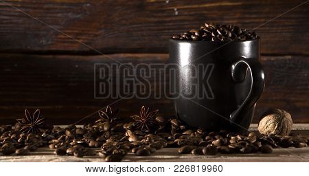 Seeds Of Coffee In A Black Cup On A Wooden Background Close Up