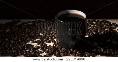 Seeds Of Coffee In A Black Cup On A Wooden Background Close Up