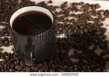 Seeds Of Coffee In A Black Cup On A Wooden Background Close Up