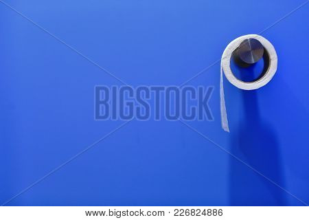 A Roll Of Toilet Paper On A Blue Wall