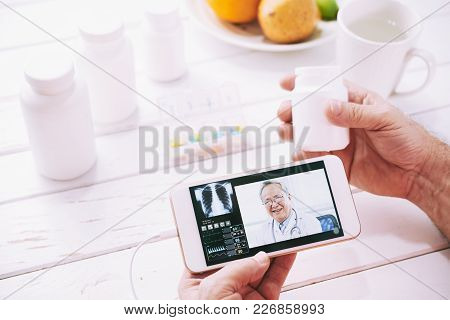 Hands Of Aged Patient Consulting General Practitioner Online On His Smartphone