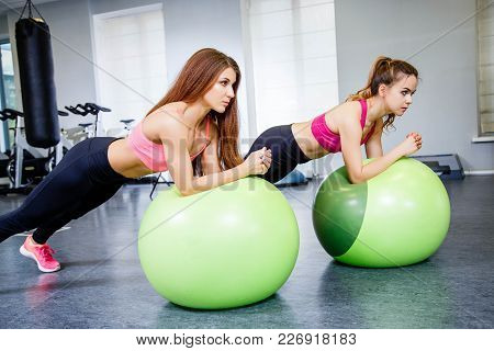 Fitness, Sport, Training And Lifestyle Concept - Two Young Woman Doing Physical Exercise With A Larg