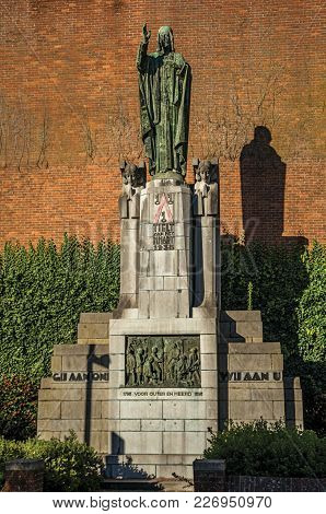 Tielt, Western Belgium - July 02, 2017. Monument, Brick Building Facade And Green At Sunset In The C