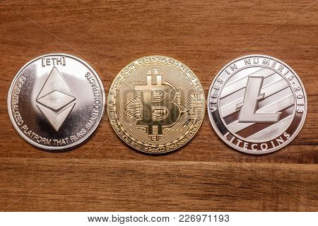 Three Coins Bitcoin Ligtecoin Ethereum Virtual Moneyon Wooden Background