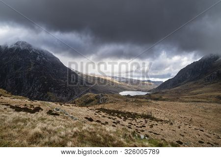 Hikers In Ogwen Valley Winter Landscape With Snowcapped Pen Yr Ole Wen And Tryfan Mountains With Dra